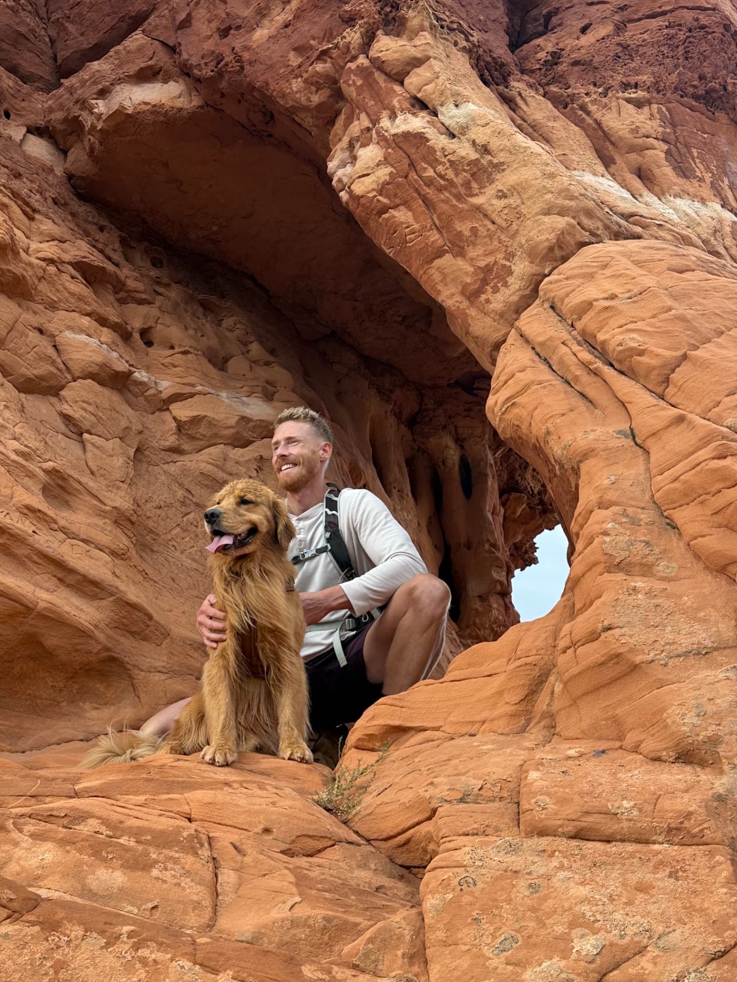 Nate Langley smiling beside his golden retriever in a red rock alcove