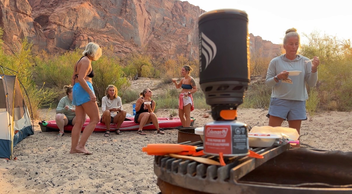 The group sharing a camp meal on the riverbank at dusk
