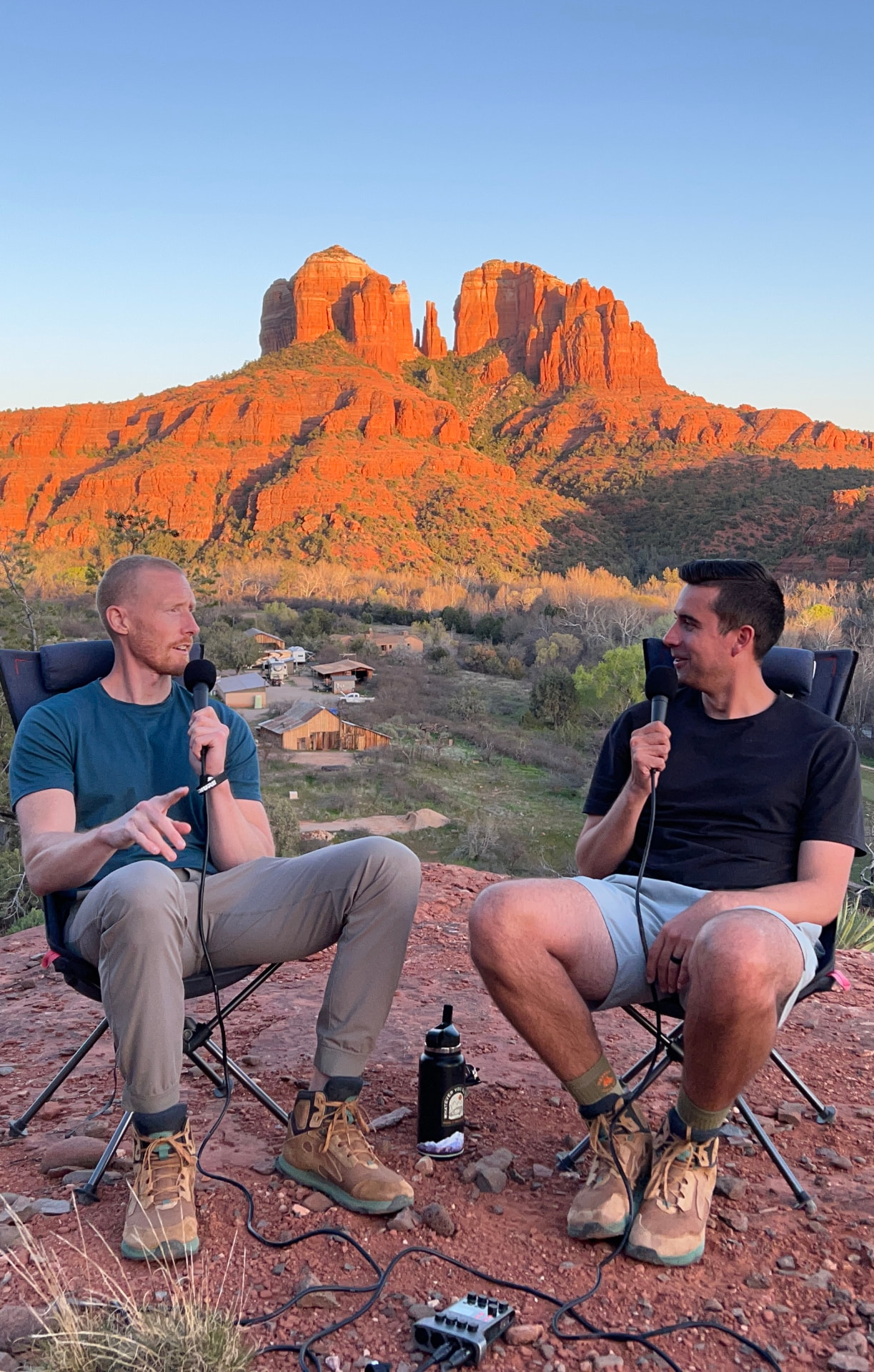Two people recording a conversation outdoors with Sedona red rocks behind them