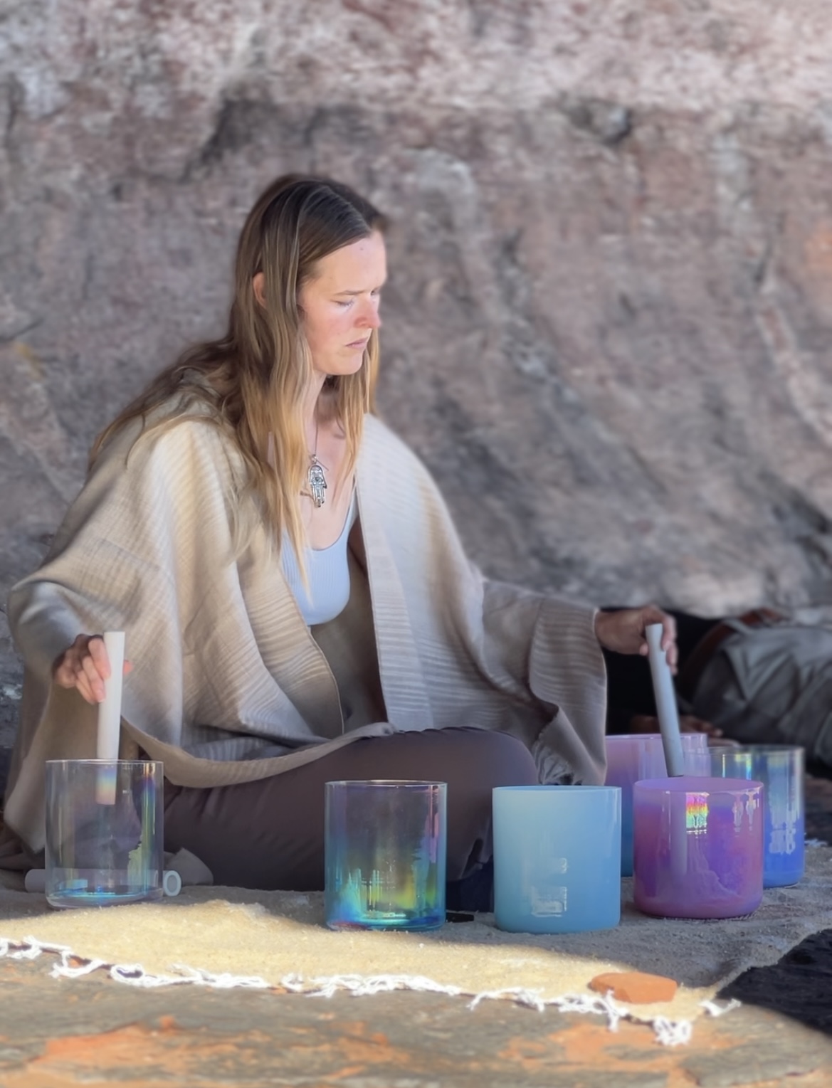 A woman leading a sound bath session against red rock