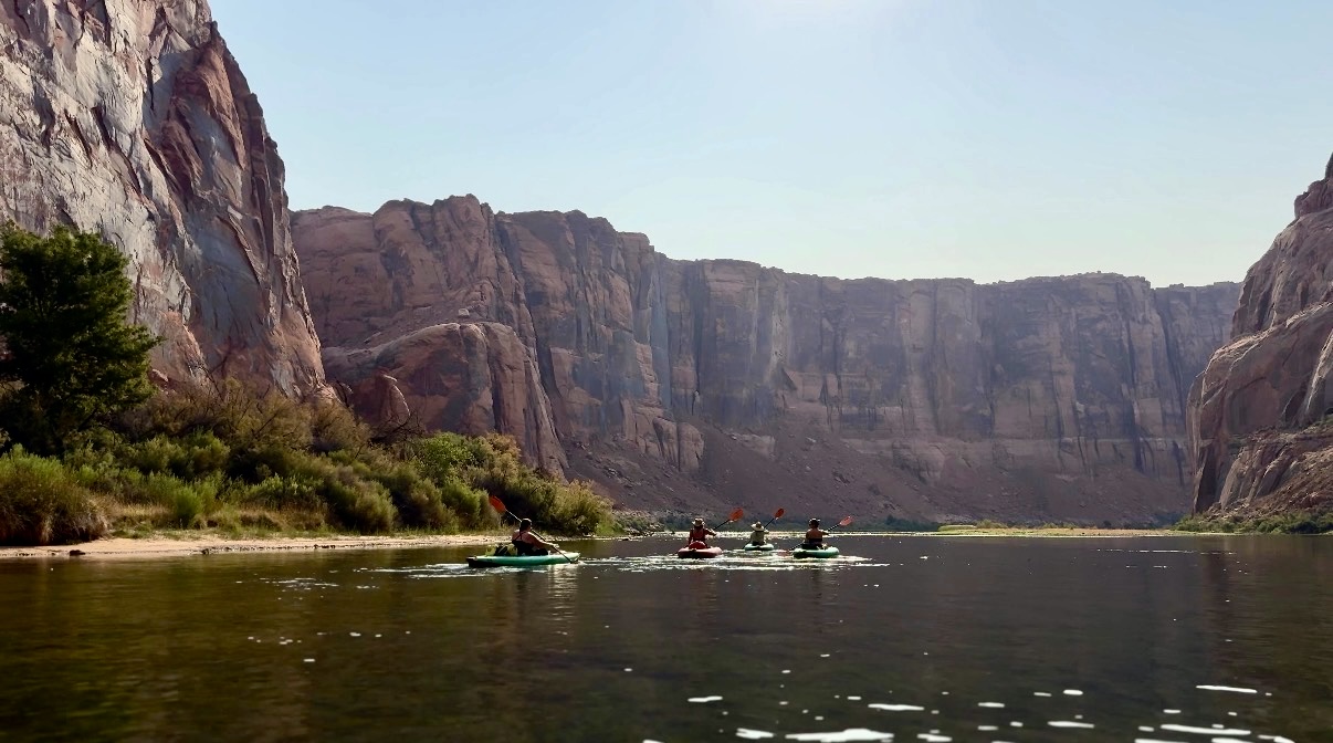 Kayakers paddling a calm stretch of river beneath tall canyon walls