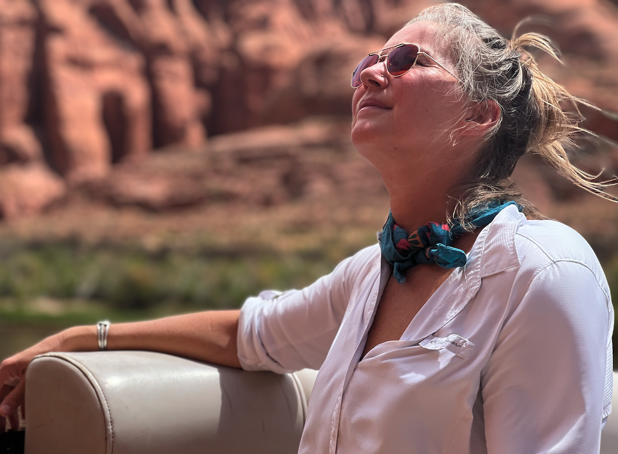A woman looking up toward the sun with Sedona red rocks behind her